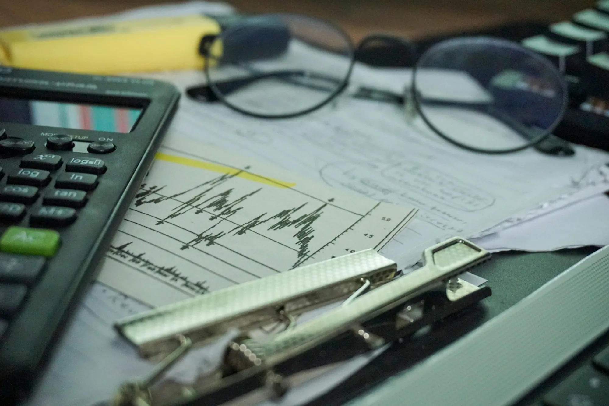 Calculator, glasses and financial charts on a clipboard