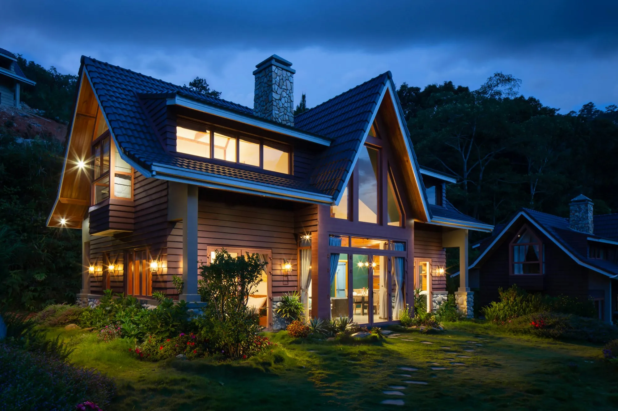 Craftsman-style home with a dark shingle roof lit up in the evening