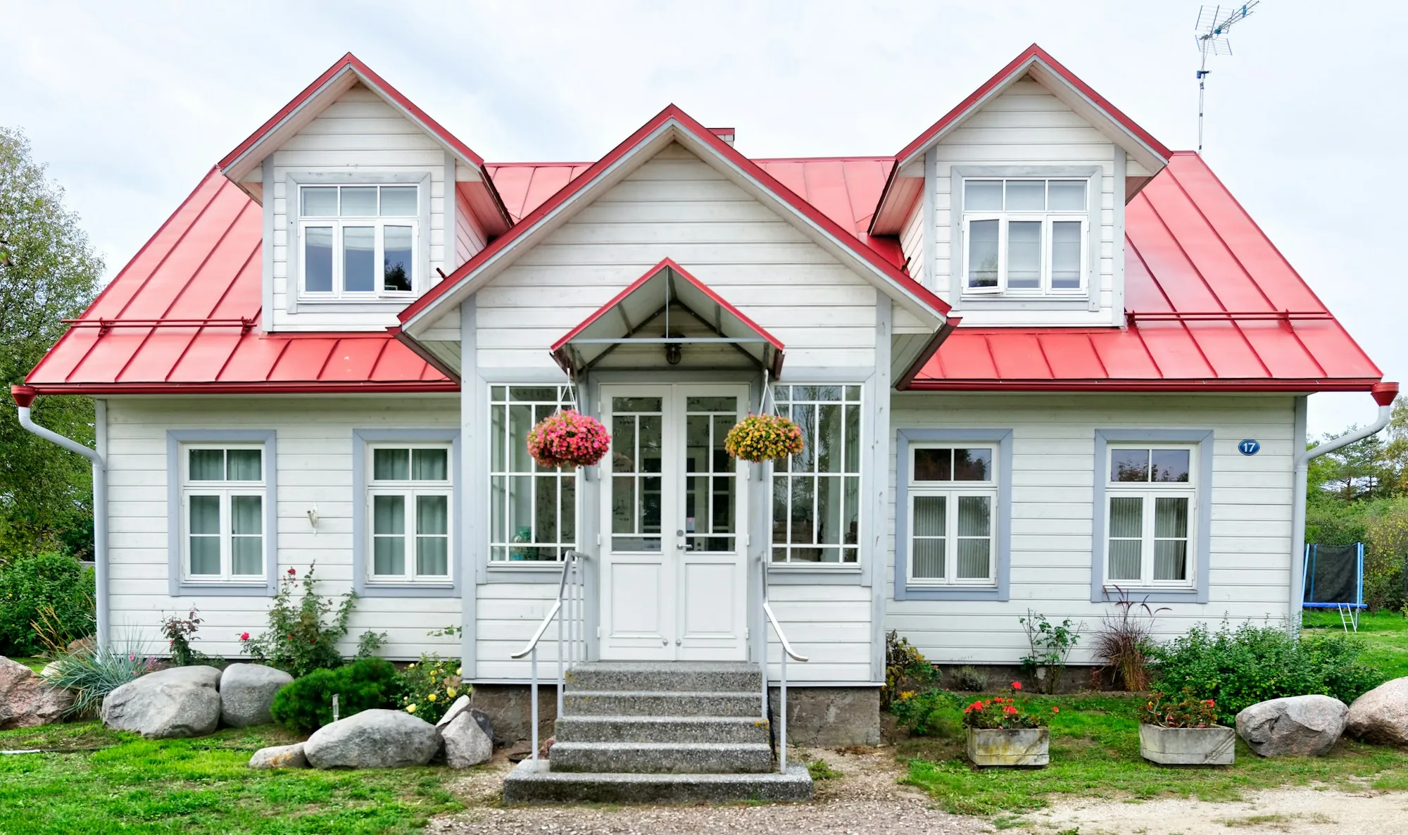 White house with a bright red metal roof and dormers