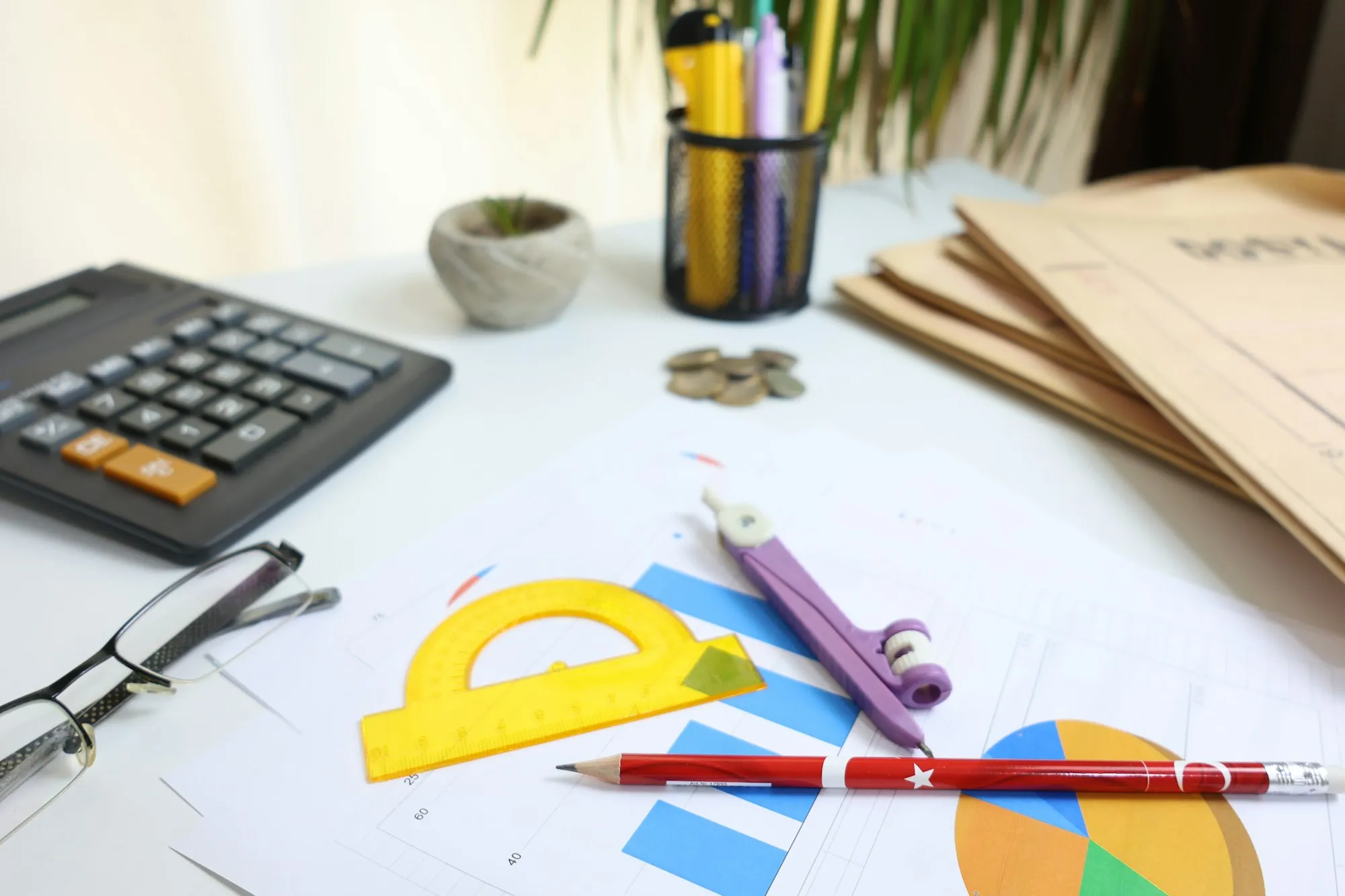 Office desk with a calculator, pens and printed charts