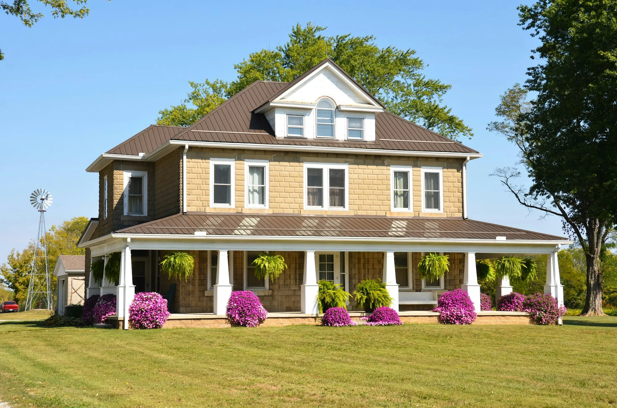 Foursquare home with a brown shingle roof and wraparound porch