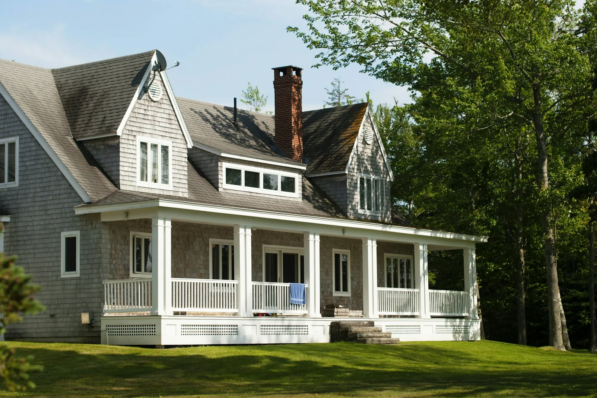 Shingle-sided home with a steep gray roof and white front porch
