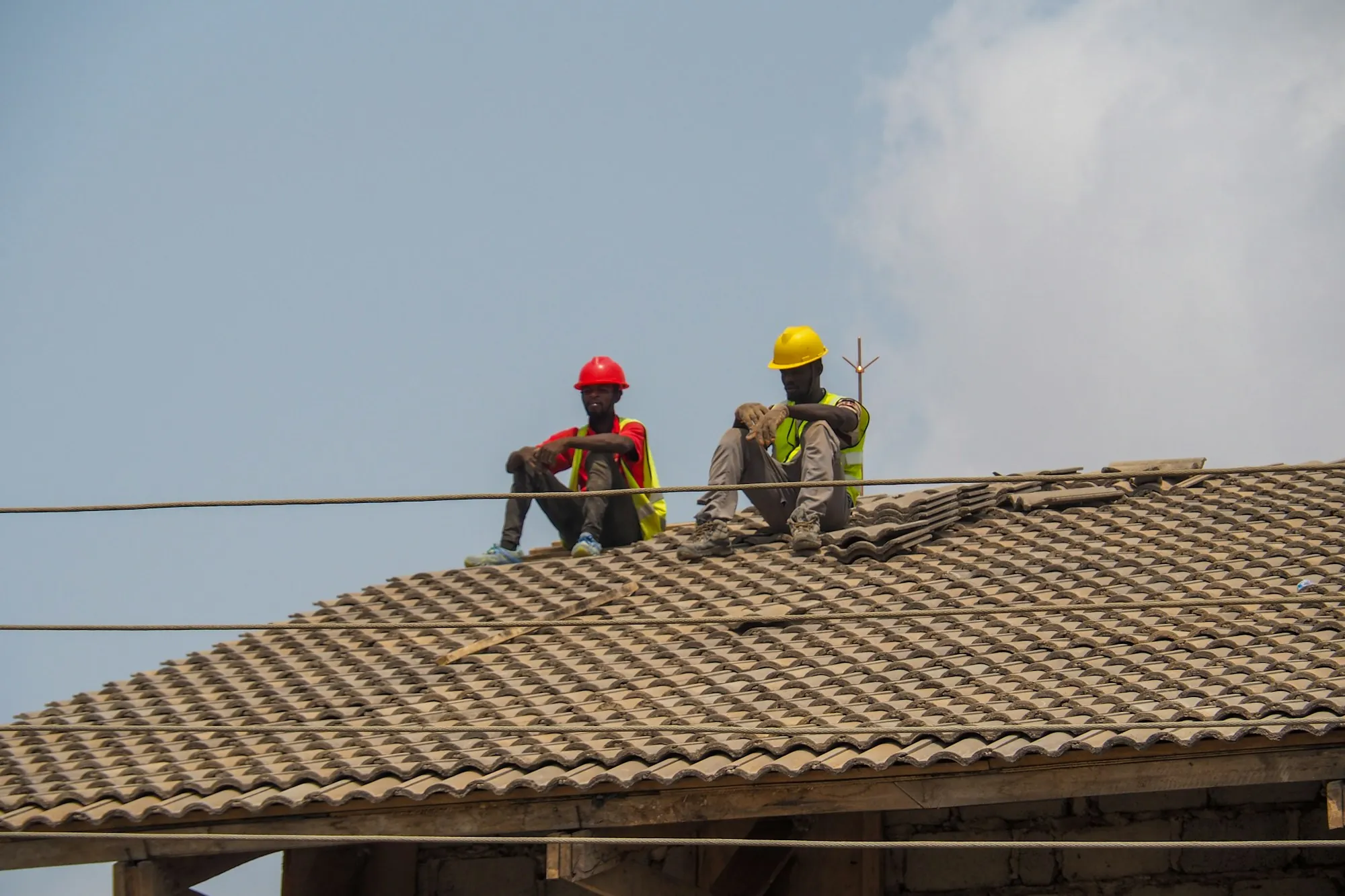 Two roofers in hard hats working on a pitched tile roof