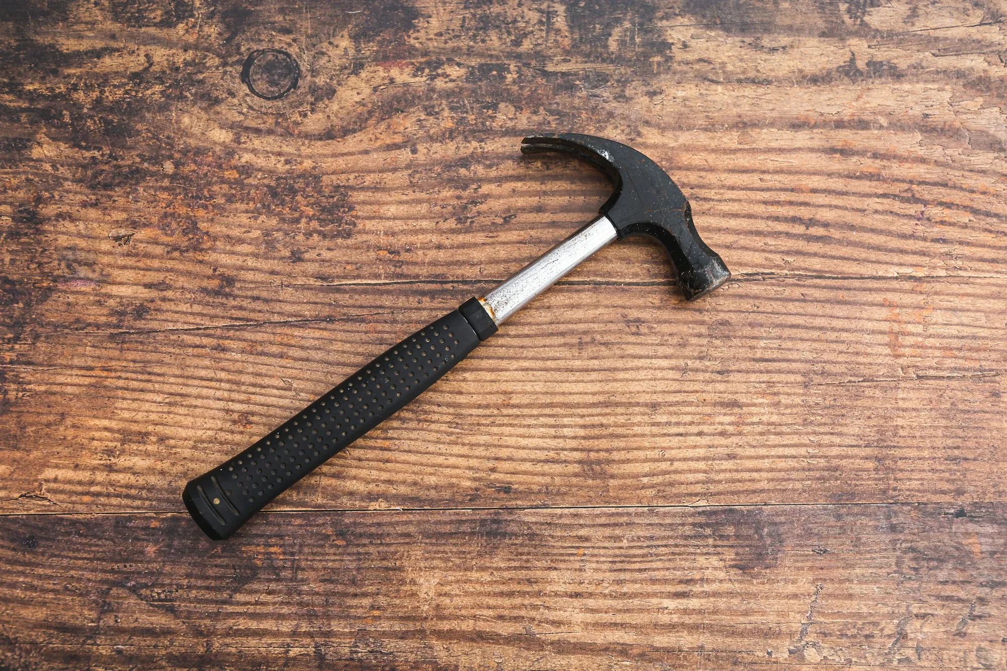 Claw hammer lying on a rustic wood surface